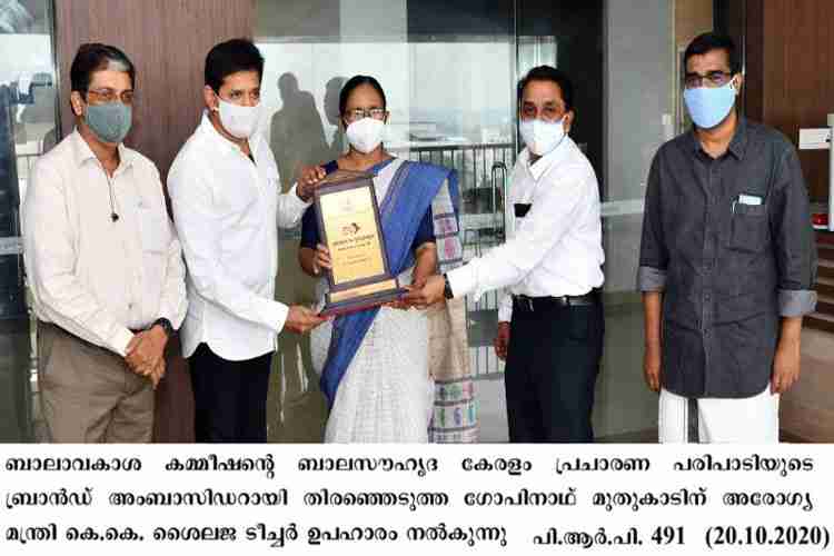 Minister K. K. Shailaja presents a memento to Bala Souhruda Keralam ambassador Gopinath Muthukad